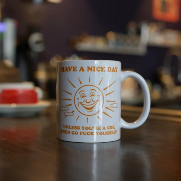 mug with drawing of a sun and text that reads Have a nice day, unless you're a cop go fuck yourself.